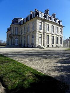 a large stone building sitting on top of a lush green field under a blue sky