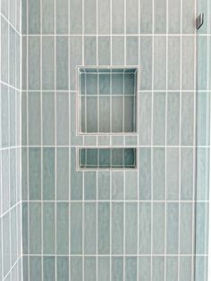 a bathroom shower with blue tile on the walls and floor, along with a square window in the middle