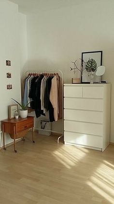 a white dresser sitting next to a bed in a bedroom on top of a hard wood floor