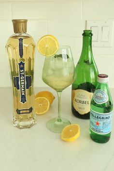 bottles and glasses filled with different types of alcohol on a counter top next to lemons