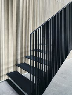 a set of black stairs next to a wall with vertical slats on the side