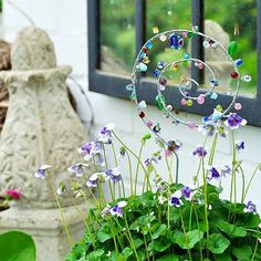 some purple and white flowers in front of a window with a circular glass decoration on it