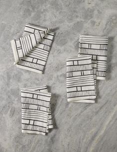 four napkins with black and white designs on them sitting on top of a table