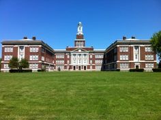 a large building with a clock tower in the middle of it's front yard