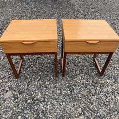 two wooden nightstands sitting on top of gravel covered ground with one drawer open and the other closed