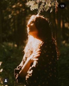 a woman is standing in the woods with her eyes closed and she has long hair