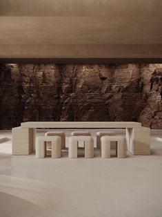 a table and stools in front of a large rock wall