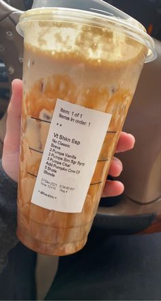 a person holding up a plastic cup filled with liquid and information about the drink in it