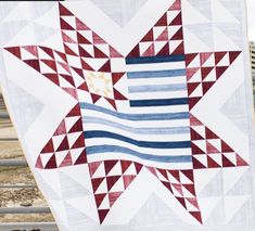 a red white and blue quilt hanging on a fence