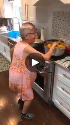 an old woman is cooking in the kitchen with her hands on the stove and looking at something