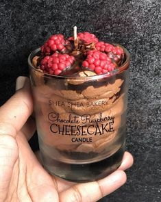 a hand holding a glass filled with raspberries