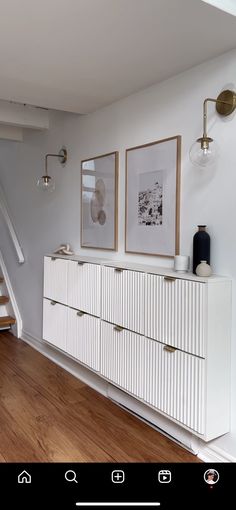 a white dresser sitting in the middle of a living room next to a stair case