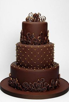 a three tiered chocolate cake with gold decorations