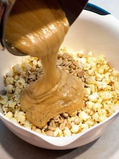 a person pouring peanut butter into a bowl of popcorn