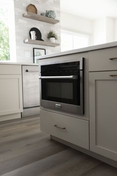 an oven in the middle of a kitchen with white cupboards and drawers on either side