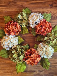 a wreath made out of flowers and leaves on a wooden table with wood flooring