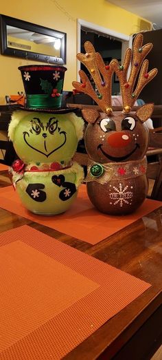 two christmas decorations sitting on top of a wooden table in front of a man wearing a hat