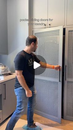 a man is standing in front of a cabinet with holes on it and pointing at the door