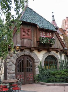 an old style house with red chairs and tables in front of the entrance to it