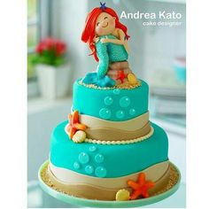 there is a blue cake with a little mermaid on top and starfish around the edges