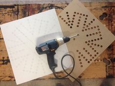 a power drill is sitting on top of some cut out paper with holes in it