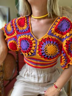 a woman with blonde hair wearing a colorful crochet top