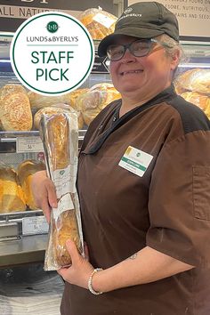 a woman holding a bag of bread in front of a display case at a store