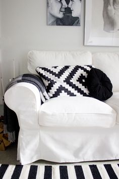 a white couch sitting in a living room next to a black and white striped rug