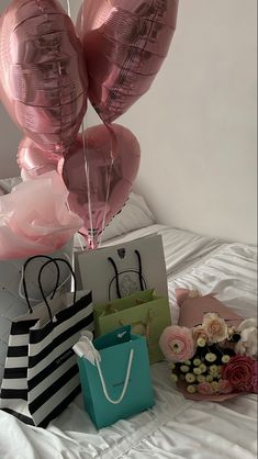 pink heart shaped balloons and shopping bags on a bed