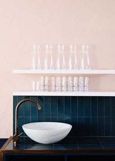 a bathroom sink sitting under a shelf filled with glasses