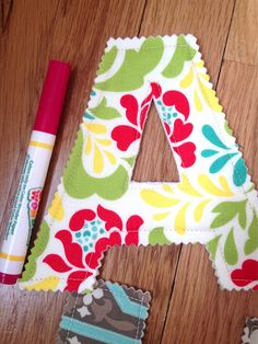 the letter a is made out of fabric and has flowers on it, along with a cricut pen