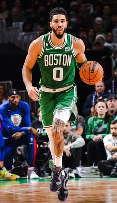 boston basketball player dribbling the ball down the court while fans watch from the stands