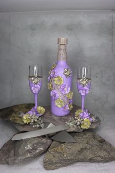 a bottle and two wine glasses sitting on top of a rock next to a knife