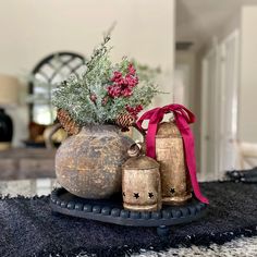 an arrangement of vases and bells on a rug in a living room with a red ribbon