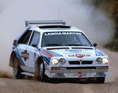 a white rally car driving down a dirt road