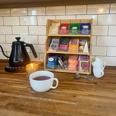 a cup of tea sitting on top of a wooden table next to a coffee pot