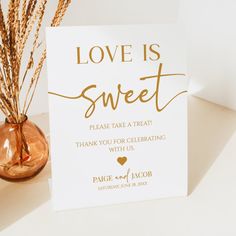 a card with the words love is sweet on it next to a vase filled with dry grass