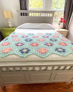 a crocheted bedspread on top of a bed in a room with hardwood floors