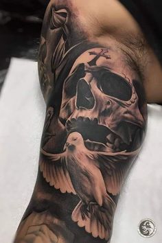 a man's arm with a skull and two birds on it, while he is wearing