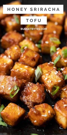 honey sriraca tofu on a black plate with green onions and sesame seeds