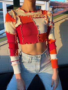 a woman sitting on top of a couch wearing a red and white cropped sweater