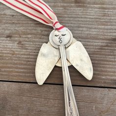 a spoon with a face on it is hanging from a red and white striped ribbon