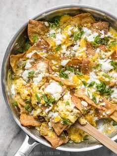 a pan filled with nachos and cheese on top of a marble countertop