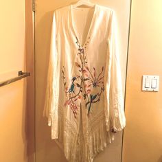 Never Worn- White, Poly-Blend With Colorful Bird And Flower Embroidery; Has Fringe At End Of Sleeves And Across The Bottom But Fringe Is Connectedweird Design But Super Hippie Pretty; Side Zip, Size M Spring Festival Embroidered V-neck Dress, Bohemian V-neck Embroidered Dress For Brunch, Spring Festival V-neck Embroidered Dress, Bohemian Embroidered V-neck Dress For Spring, Spring Embroidered Dress For Beach Cover-up, Long Sleeve Embroidered Beach Dress For Spring, Bohemian Long Sleeve Embroidered Dress For Spring, Bohemian V-neck Embroidered Dress For Spring, V-neck Embroidered Dress For Spring Festival