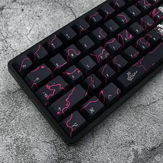 a black and pink computer keyboard sitting on top of a stone floor with the keys lit up