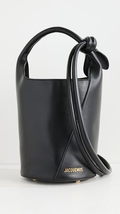 Find JACQUEMUS Le Petit Tourni on Editorialist. Cowhide. Gold-tone logo emblem and hardware. Structured base. Knotted shoulder strap. Patch and zip interior pockets. Magnetic snap. Suede lining. Weight: 20oz / 0.57kg. Made in Italy. Measurements: Height: 9.5in / 24cm Length: 7.75in / 19.5cm Depth: 7.75in / 19.5cm Strap drop: 10.75in / 27cm Handle drop: 5in / 12.5cm Neon Bag, Black Cow, Logo Emblem, Leather Bucket Bag, Leather Bucket, Emblem Logo, Metallic Logo, Blue Bags, Cow Leather