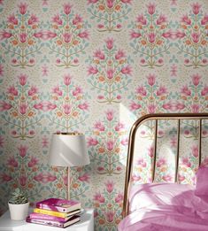 a bedroom with pink and blue wallpaper, a gold bed frame and a white nightstand