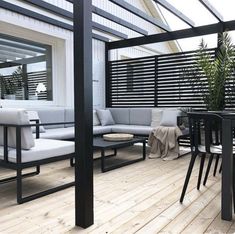 an outdoor living area with wooden flooring and black metal furniture on the outside deck