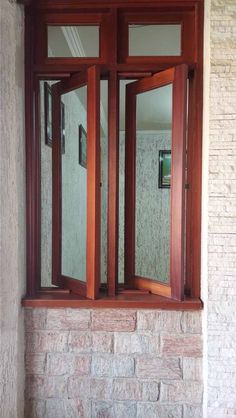 an open window on the side of a building with wooden trim and glass panes