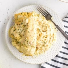 a white plate topped with pasta covered in gravy next to a knife and fork